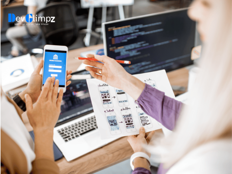 Team members at DevGlimpz collaboratively developing a mobile app, showing a phone with the app interface, wireframe sketches, and coding screens, representing comprehensive mobile app development services.
